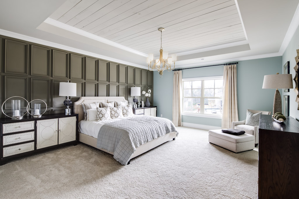 The bold board and batten wall combined with a shiplap tray ceiling makes this a captivating master bedroom.