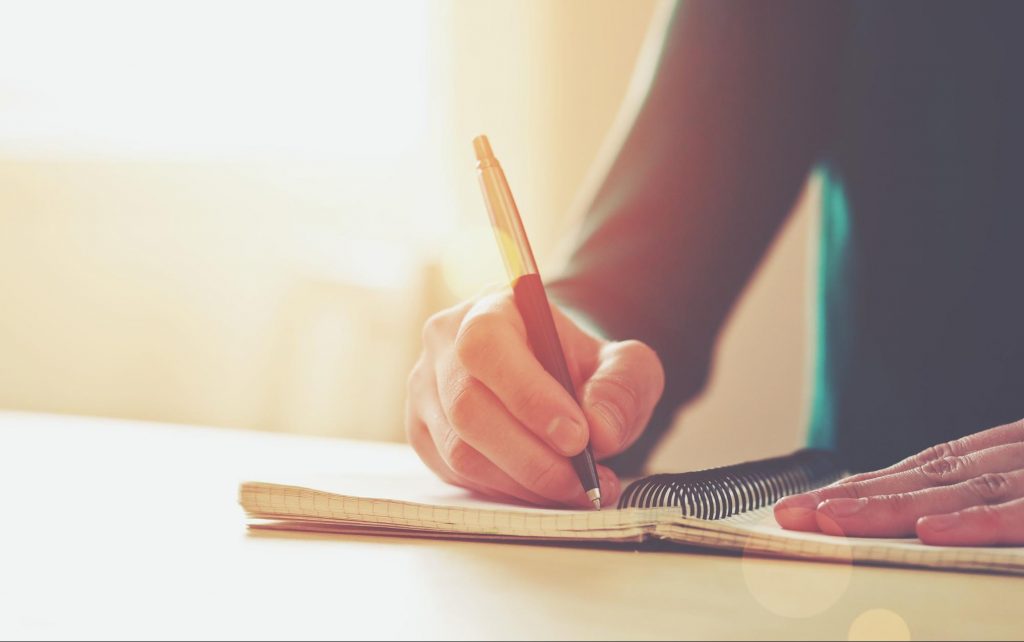 a person writing in a notebook
©Ivan Kruk