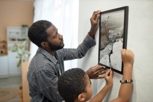 father and son hanging up a picture on a wall