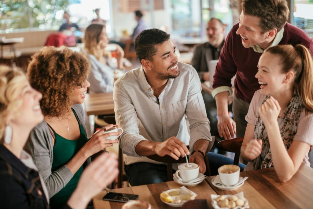 Group of friends laughing and enjoying coffee together at a local café