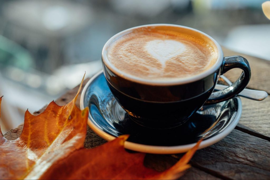 Seasonal fall coffee with latte art and autumn leaves ©Okrasiuk