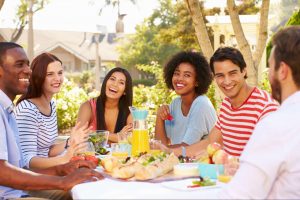 Friends enjoying an outdoor meal together in a neighborhood setting. ©Monkey Business Images