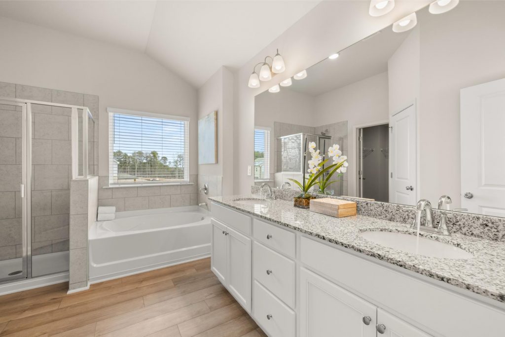 Primary suite at Alcovy Village with sitting area, spacious bedroom, and ensuite bath with garden tub.