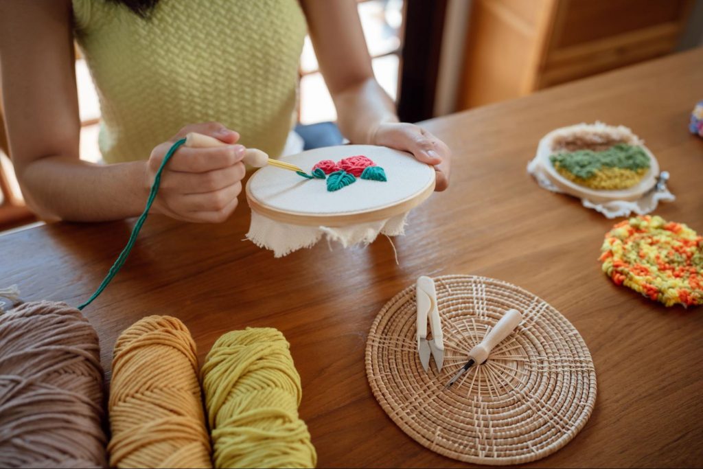 A person cross-stitching a flower design as part of their phone free activities in a light-filled home. ©CharliePix