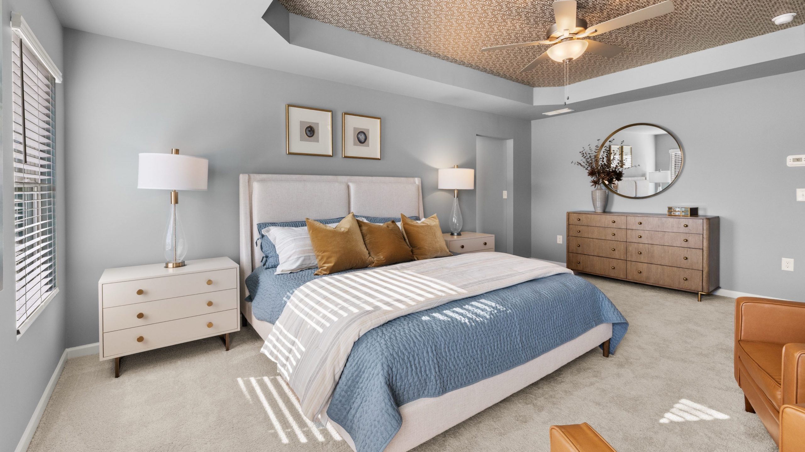 Decorated primary bedroom with accented coffered ceiling, carpet, and light gray walls