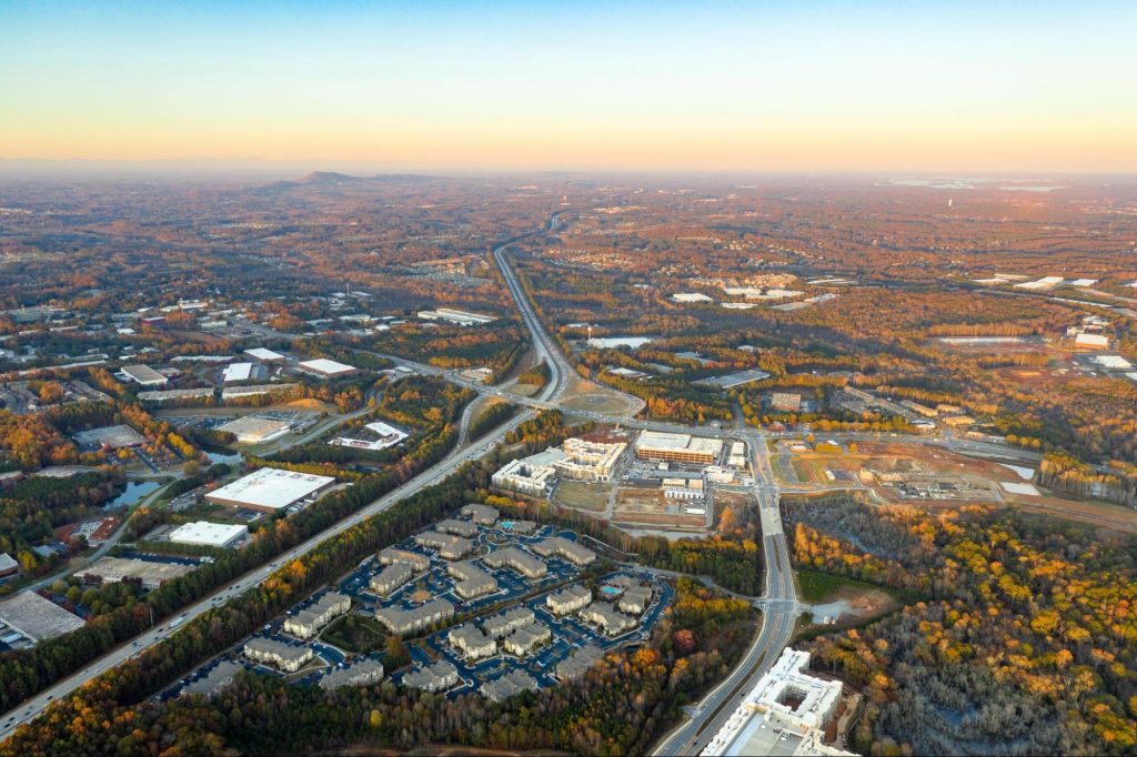 Aerial sunset view of the GA-400 highway corridor surrounded by autumn foliage and commercial developments, connecting Forsyth County to Metro Atlanta. ©RodClementPhotography